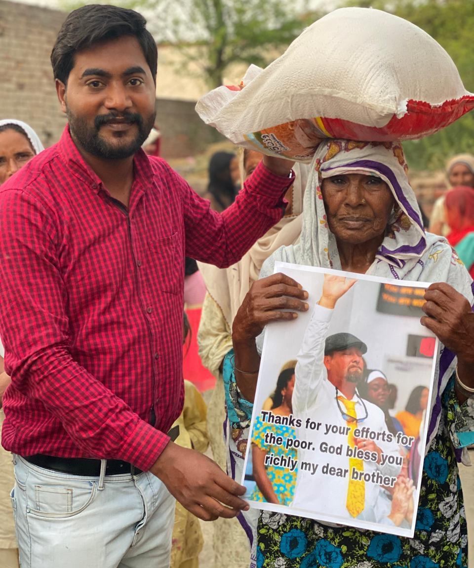 Mission worker with elderly woman holding a blessing message